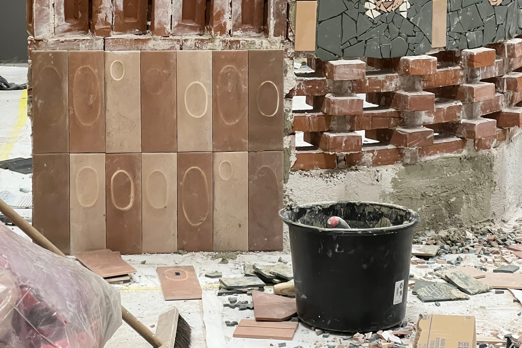Byggeplass med murverk og murerbøtte og flere knuste fliser på gulvet
