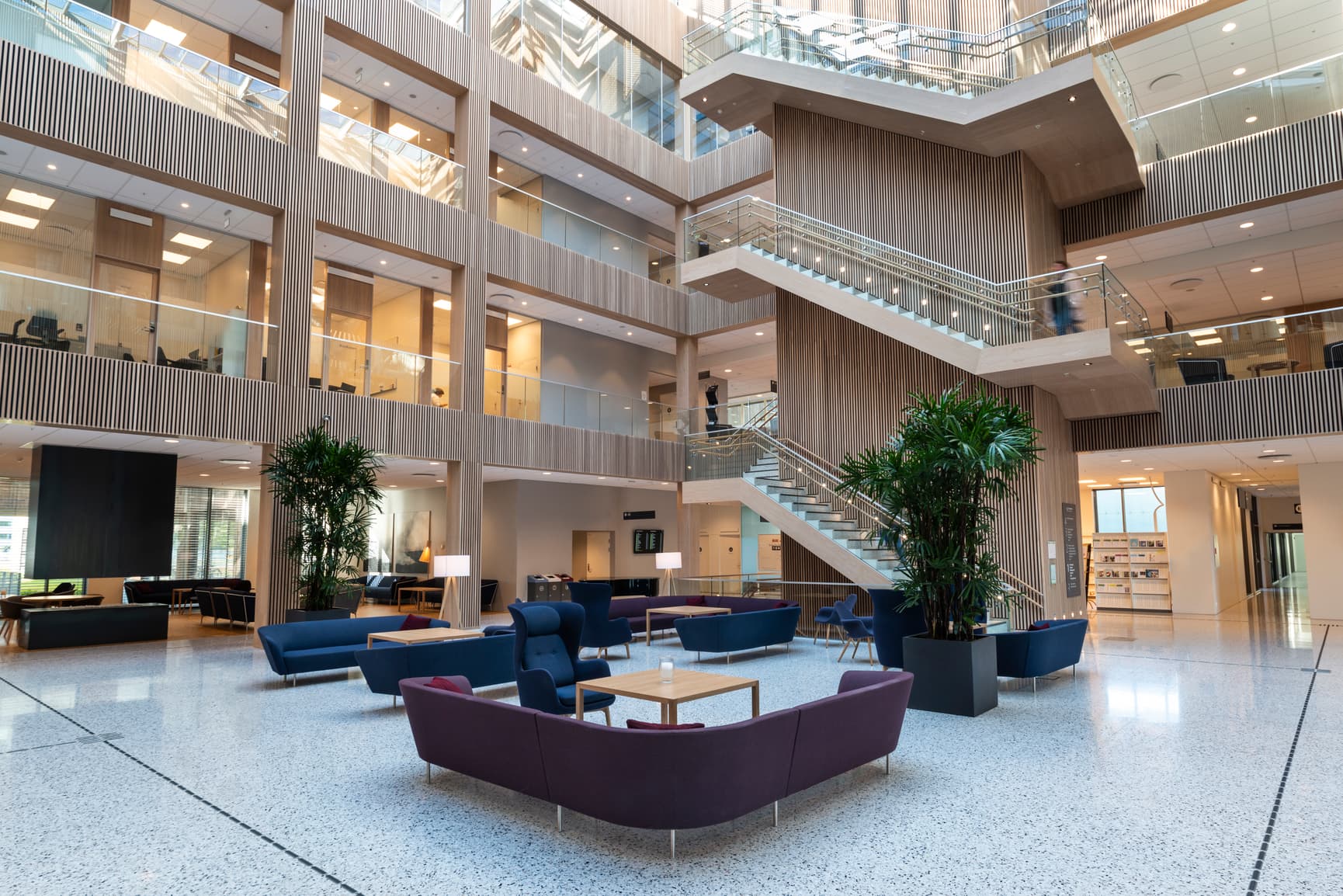 Foaje ved sykehus med terrazzo på gulv og møbler i dyp lilla og mørk blå
