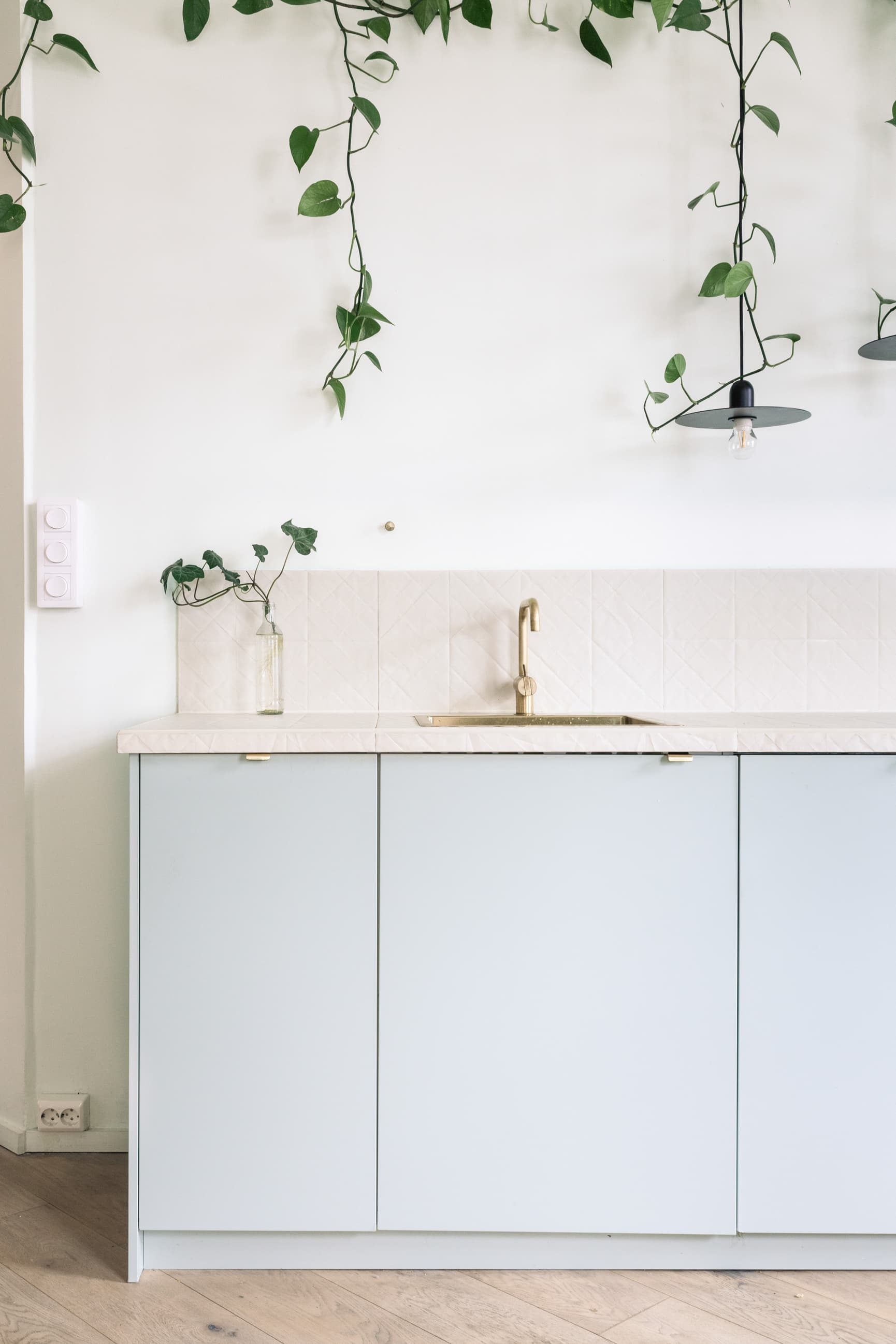 Lyst og delikat kjøkken med lyseblå fronter og en offwhite flis som både benkeplate og backsplash